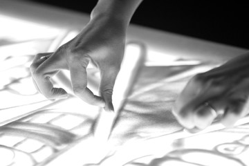Sand animation. Girl's hands drawing sand closeup In black and white