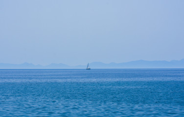 Fototapeta na wymiar Faraway sailing boat on the blue sea