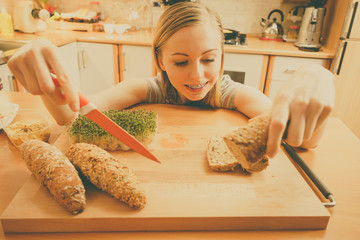 Woman in kitchen holding knife making healthy sandwich