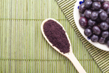 Fruits and acai powder originating from the Amazon on wood (Euterpe oleracea)