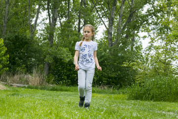 Little girl  playing with poplar fluff on the green park outdoor.