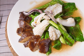 Stir fried kale with fresh squid on white dish