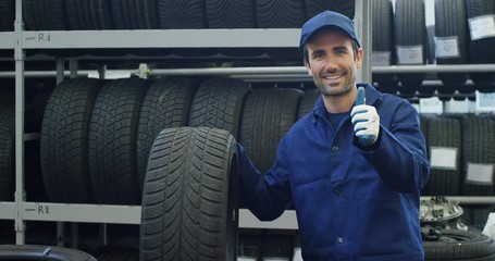Portrait of a young beautiful car mechanic in a car service, in the background of rubber. Concept: repair of machines, fault diagnosis, repair specialist, technical maintenance and on-board computer.