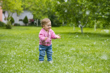 Little baby girl  playing with poplar fluff on the green park outdoor.