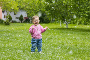 Little baby girl  playing with poplar fluff on the green park outdoor.