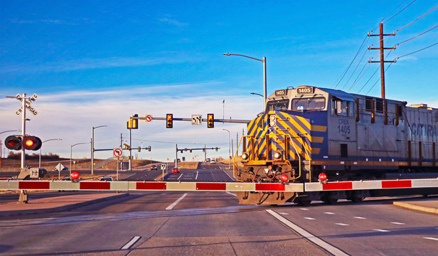 A train crosses a busy street at a railroad crossing
