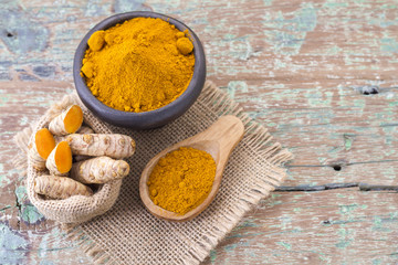 Roots and turmeric powder on wood background (long curcuma)