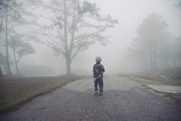 Little boy walking through the mist in forest : Thailand