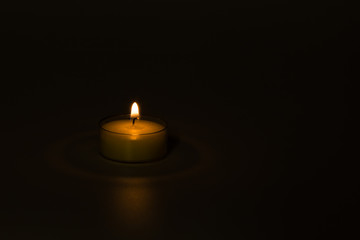 Small lit candle with soft light isolated on dark background