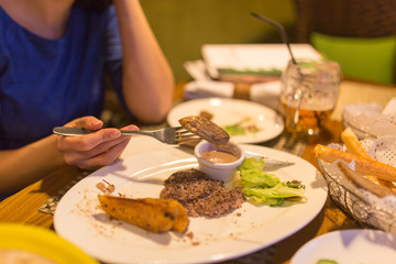 Girl eating meat with salad in a restaurant