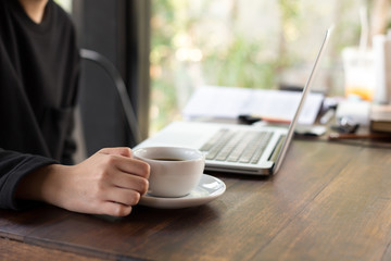 Student is hand holding cup of coffee