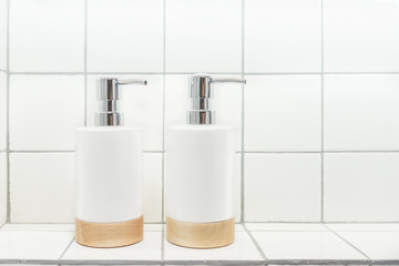 Soap and shampoo dispensers on a white mosaic shelf of bathroom interior