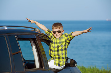 Portrait of a smiling boy in the car in the background of the sea . The concept of leisure and travel