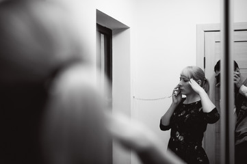 blonde woman answers the intercom call, hold the phone to his ear, waiting for the arrival of the long-awaited guest. Being in apartment near front door