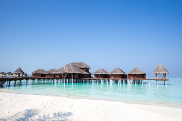 Over Water Bungalows over crystal clear blue ocean sea water with white sand beach