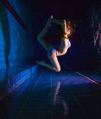 young girl in beautiful white dress posing underwater in the pool 