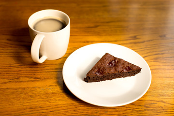 Brownie on a plate with  a cup of coffee