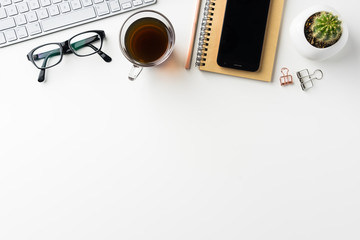 Naklejka premium Business concept - Top view of white desktop background with notebook, coffee, smart phone, cactus and clip for mockup design