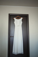 Vertical photo of ivory and white wedding dress hanging on the door