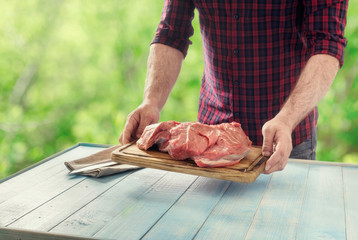 Male farmer holding fresh beef meat on chopping board