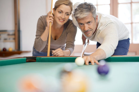 mature couple playing pool together