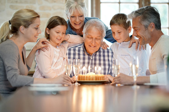 Family celebrating grandfather birthday with cake and candles