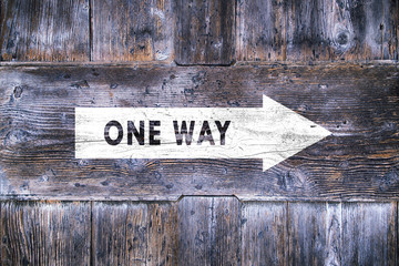 One way arrow sign on aged wooden background. Conceptual direction symbol.
