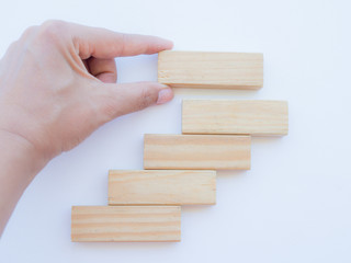 Concept of building success foundation. Women hand put wooden blocks in the shape of a staircase