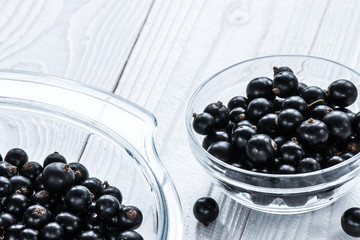 black currant in glassware on white wooden table