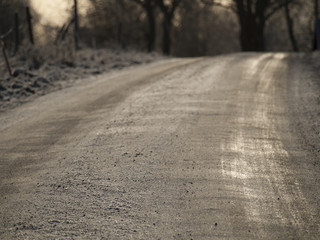 Schotterstraße mit Eis im Winter im Abendlicht