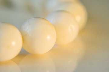 A close-up of a bracelet, a string of white onyx spheres, soft defocus.