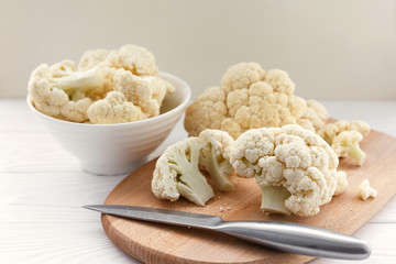Fresh cauliflower in white dishes and on a wooden table