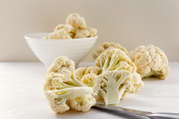 Fresh cauliflower in white dishes and on a wooden table