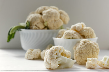 Fresh cauliflower in white dishes and on a wooden table