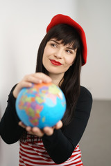 frau mit roter mütze hält eine weltkugel in der hand