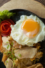 Asian noodles with fresh green onion and fried egg on old wood table