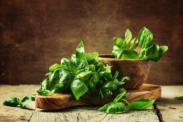 Fresh green basil in olive mortar with pestle, vintage wooden background, rustic style, selective...
