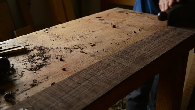 Luthier sanding wood with a wood planer to manufacture a new guitar in workplace