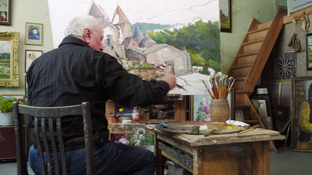 An elderly artist writes a picture in his studio 4k