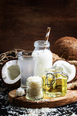 Coconut products set: milk, water, oil, shavings, dark background, selective focus