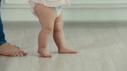 Legs of mother and baby. The baby's first steps