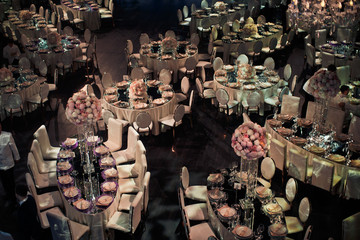 Look from above at mirror tables and white chairs in dark hall