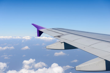 Obraz premium Wing of the plane flying above the clouds. View from the window of an airplane