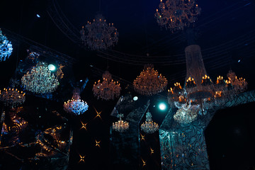 Crystal chandeliers hang from the dark ceiling in the restaurant