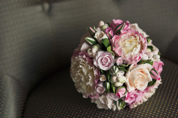 Pink bouuqet of roses and buds lies on brown chair