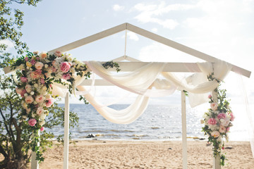 White cloth hangs from wedding altar decorated with pink flowers