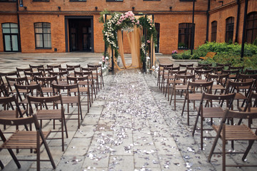 Brown chairs stand side by side before orange wedding altar outside