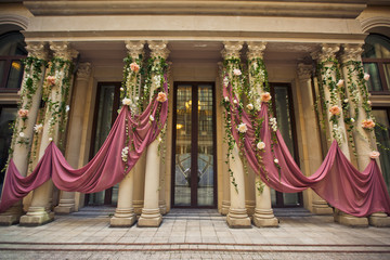 Pillars before the entrance to the house decorated with pink cloth and flowers