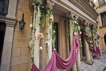 Pillars decorated with pink cloth and flower garland stand prepared for wedding ceremony