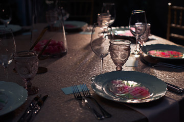 Wineglasses stand before plates with pink menu cards